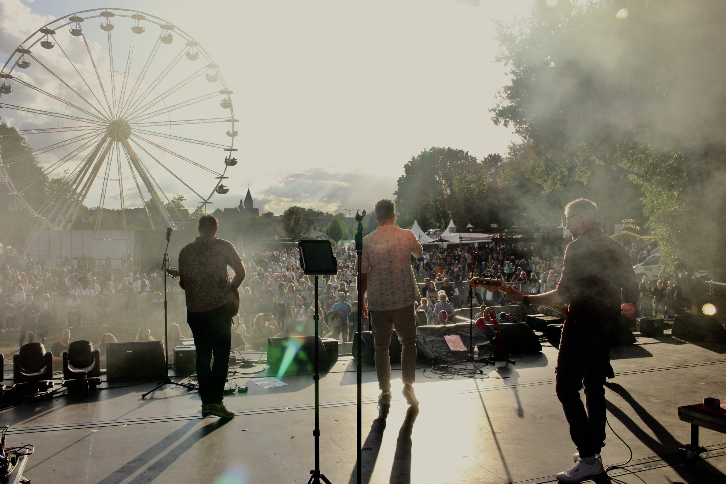 Blick von der Bühne ins Publikum beim Parkfest, dahinter das Riesenrad im Gegenlicht